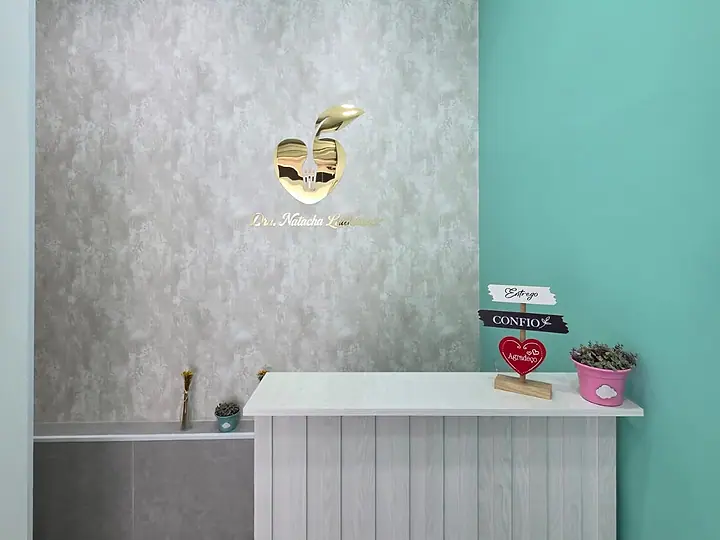 Balcão de recepção branco com o logo dourado na parede