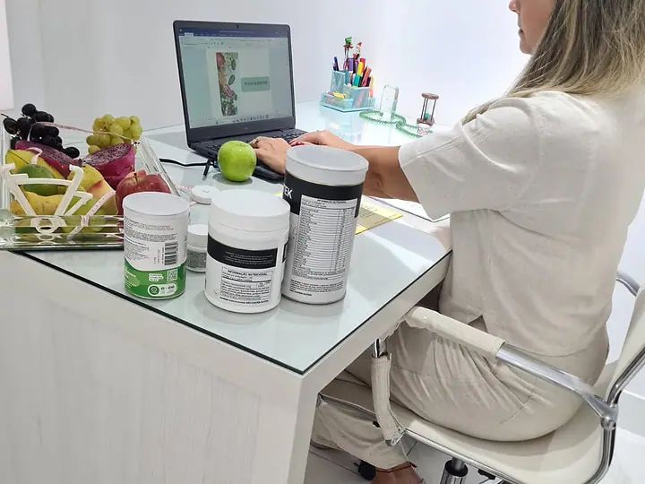 Natacha Ludkiewicz ao computador, de costas, preparando um atendimento