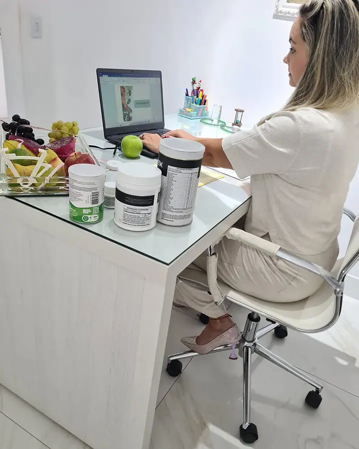 Natacha Ludkiewicz ao computador, de costas, preparando um atendimento