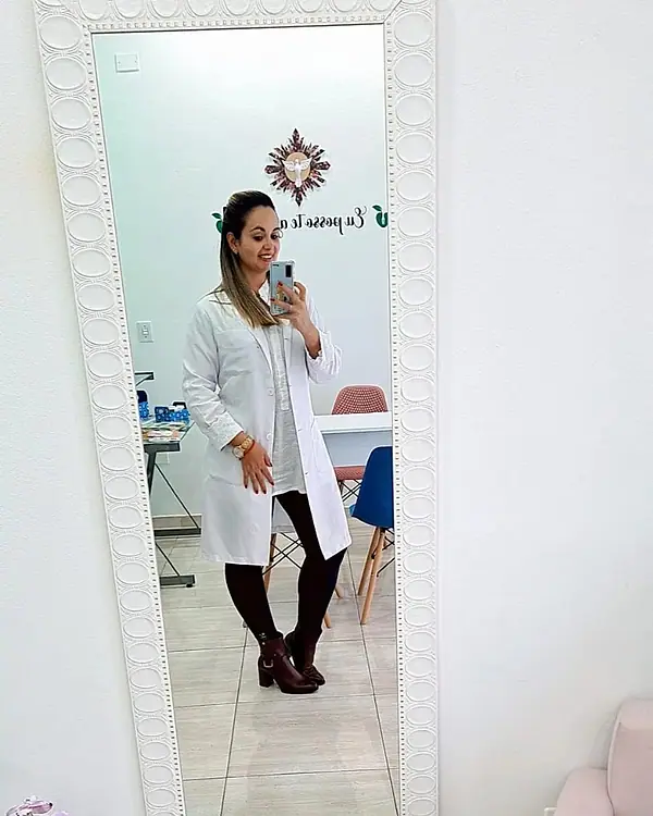 Natacha Ludkiewicz de jaleco branco, refletida no espelho do consultório