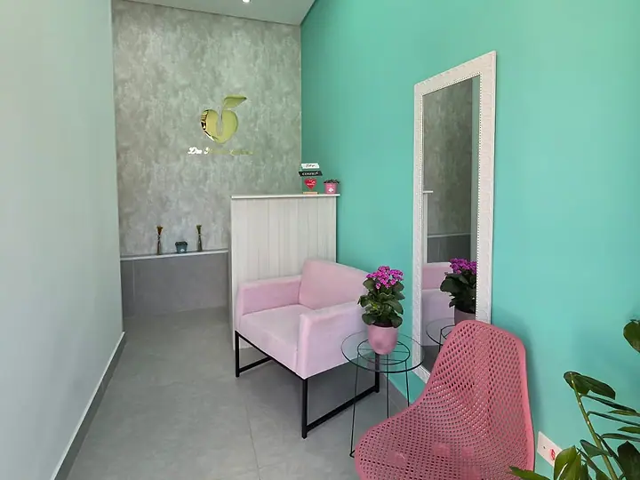 Recepção do consultório, com poltronas rosa, espelho e parede verde-água